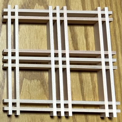 細い木のパーツを縦横に組んでいる途中のコースター